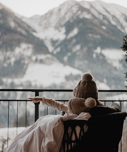 Mutter und Kind kuscheln am Balkon mit Ausblick auf die Landschaft.