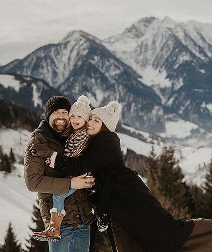 Eine Familie lacht zusammen inmitten einer Winterlandschaft.