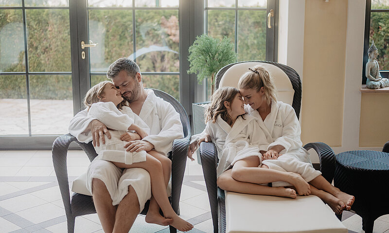Eine Familie lacht und genießt die gemeinsame Zeit im gemütlichen Ambiente des Wellnessbereichs.
