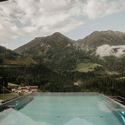 Infinity-Außenpool des Wellnesshotels Berghof in Salzburg mit beeindruckendem Bergpanorama.