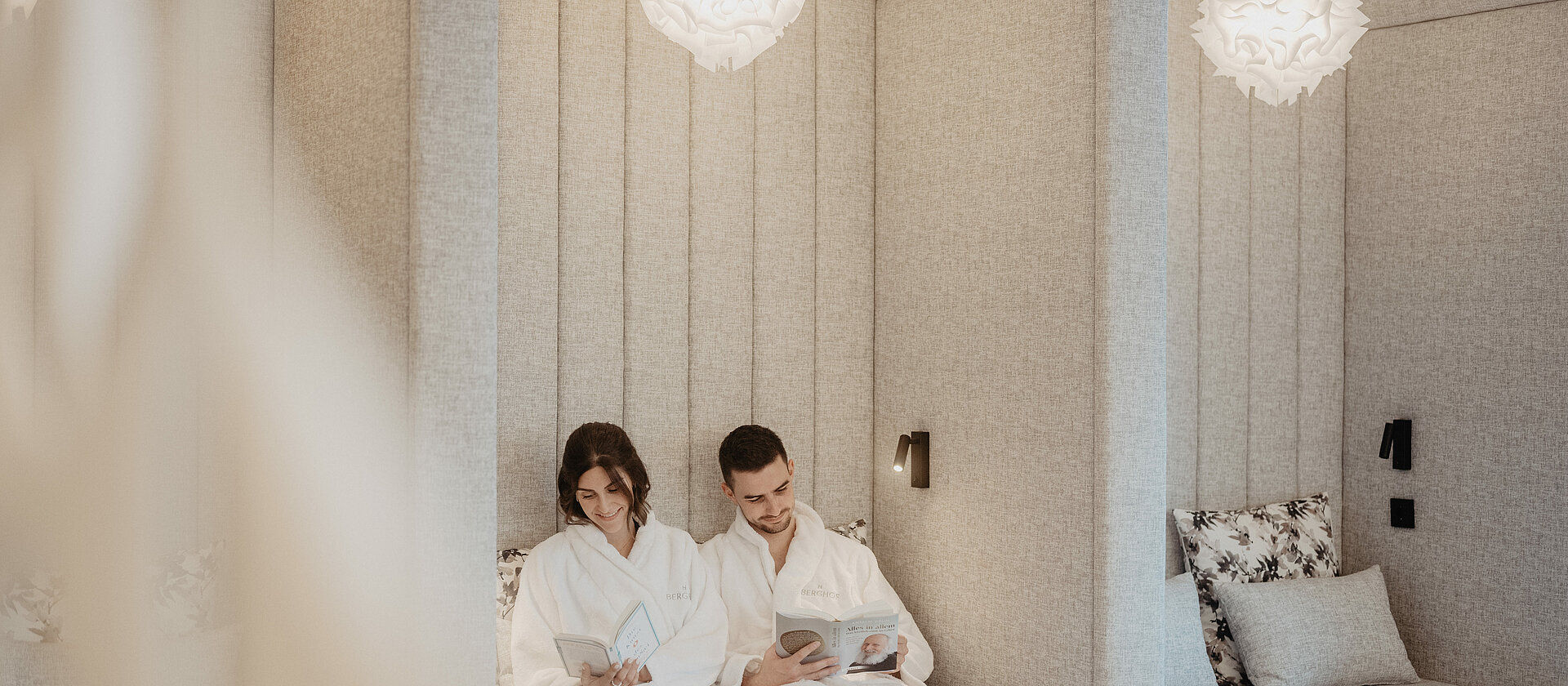 Paar entspannt im stilvollen Ruheraum des Hotel Berghof in Salzburg und liest ein Buch.
