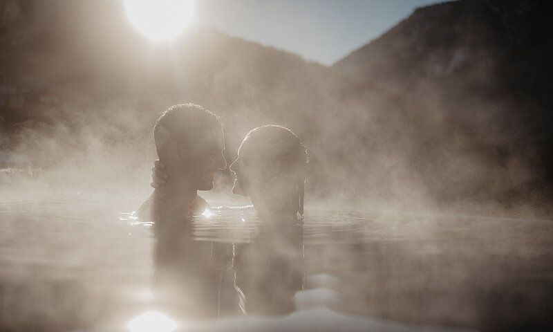 Paar genießt den Infinity-Pool mit Blick auf die Salzburger Berglandschaft im Hotel Berghof.