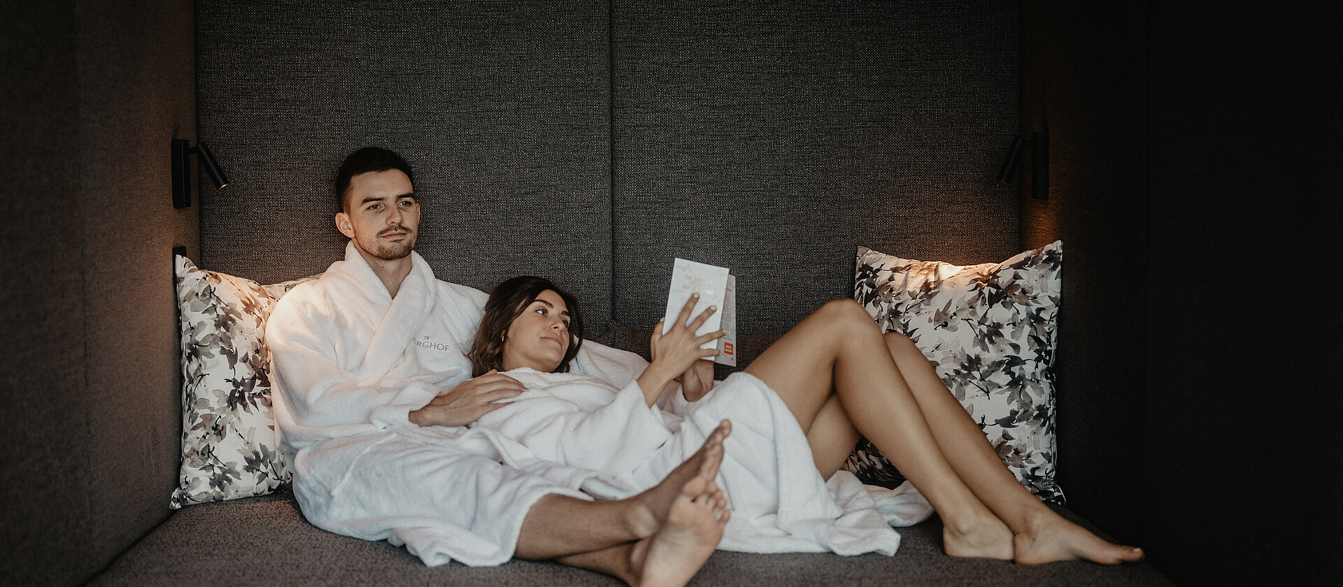 Paar entspannt im stilvollen Ruheraum des Hotel Berghof in Salzburg und liest ein Buch.