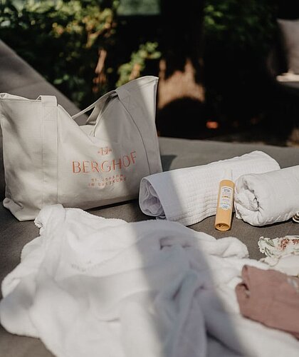 Badetasche mit Handtüchern und Sonnencreme auf einer Liege
