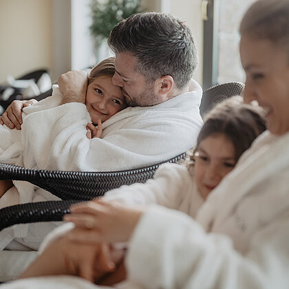 Eine Familie in Bademänteln genießt entspannte Momente im Wellnessbereich.