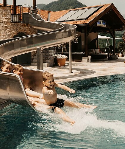 Kinder rutschen bei der Wasserrutsche am Outdoor Pool und haben Spaß