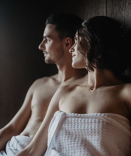 Ein Paar sitzt in der privaten Sauna im Zimmer und genießt den Moment.