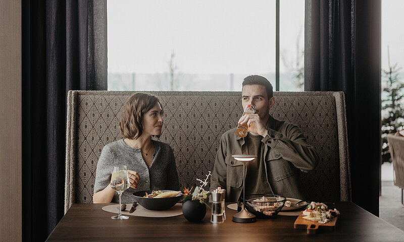 Paar genießt einen entspannten Lunch im stilvollen Restaurant des Hotel Berghof in St. Johann, Salzburg