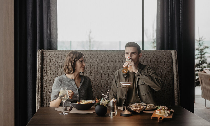Paar genießt einen entspannten Lunch im stilvollen Restaurant des Hotel Berghof in St. Johann, Salzburg