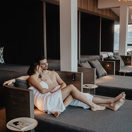 Paar entspannt im Ruheraum Goldstück und genießt den Ausblick auf die Berge.