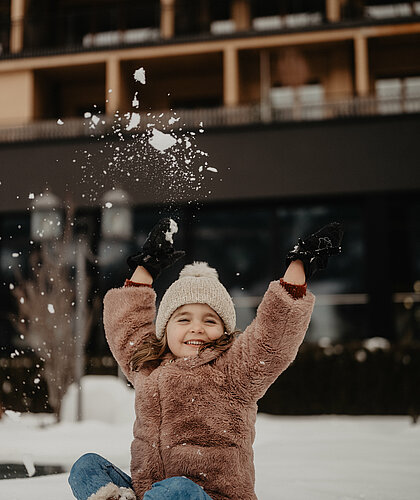 Ein Kind sitzt im Schnee und hat Spaß beim Spielen.