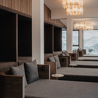 Ruheraum mit gemütlichen Liegen und Panoramafenstern mit Ausblick auf die verschneite Berglandschaft von Salzburg.