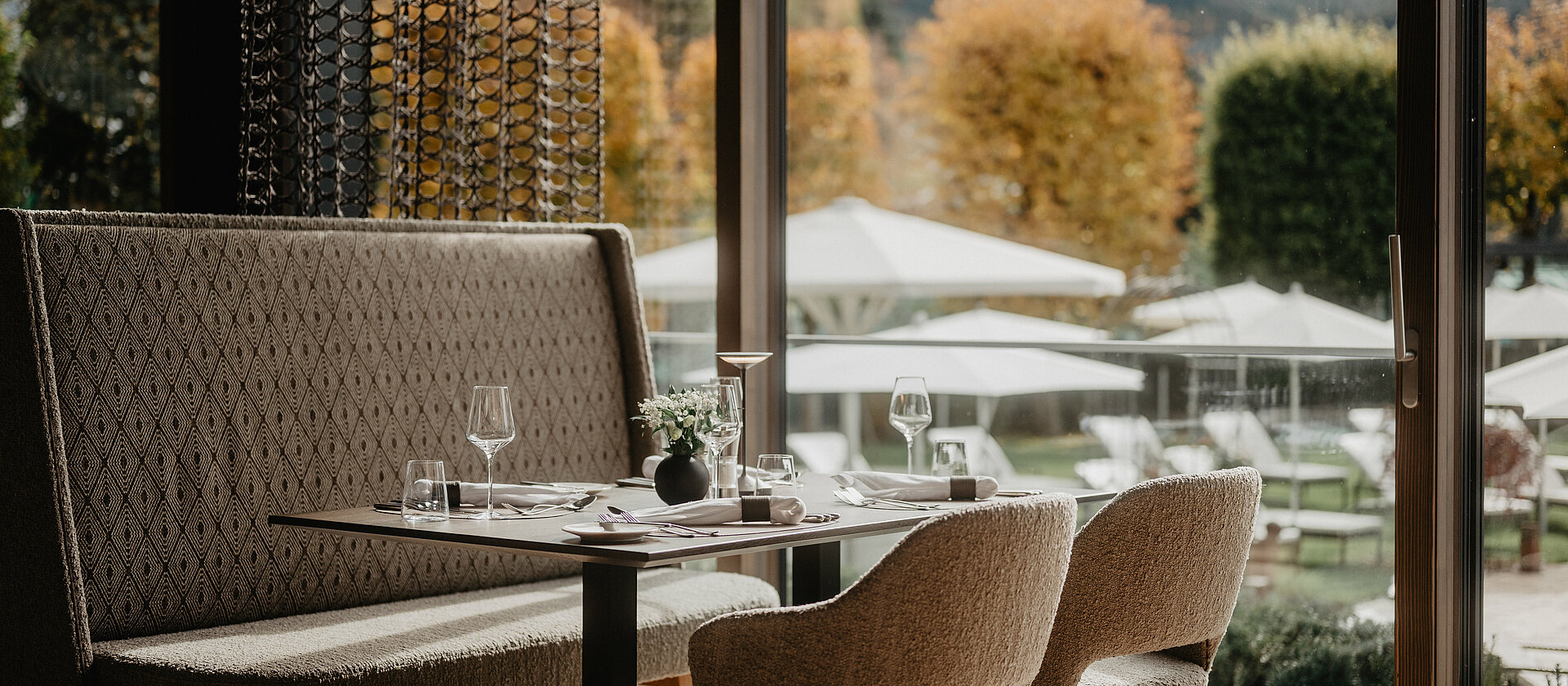 Ein Restaurant mit aufgedecktem Tisch und Blick auf herbstliche Kulisse.