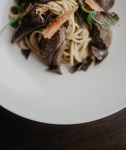  Bild 1 Dateiname: schokoladendessert-mit-frucht-hotel-berghof.jpg Alt-Text: Feines Schokoladendessert mit Beeren und kunstvoller Garnitur im Hotel Berghof in Österreich. Bild 2 Dateiname: vanillecreme-mit-birne-hotel-berghof.jpg Alt-Text: Vanillecreme mit karamellisierten Birnen und knusprigen Schokoladensplittern im Hotel Berghof. Bild 3 Dateiname: fischgericht-mit-risotto-hotel-berghof.jpg Alt-Text: Knusprig gebratener Fisch auf cremigem Risotto mit Gemüse und feiner Soße, serviert im Hotel Berghof. Bild 4 Dateiname: trüffelpasta-hotel-berghof.jpg Alt-Text: Frische Pasta mit zarten Trüffelscheiben, serviert im eleganten Ambiente des Hotel Berghof.