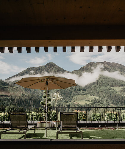 Gemütliche Liegewiese mit Sonnenschirm und herrlichem Blick auf die Berge am Hotel Berghof in St. Johann im Pongau.