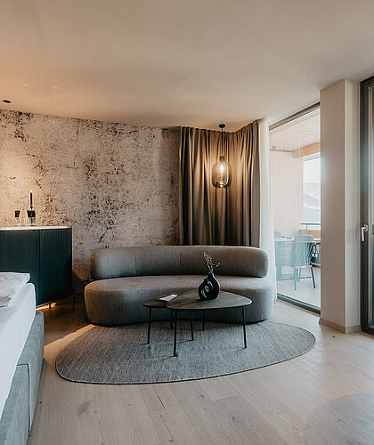 Wohnraum der Berghof Suite Premium mit Sitzgruppe, eleganter Einrichtung und Blick auf die Berge im Hotel Berghof Salzburg.