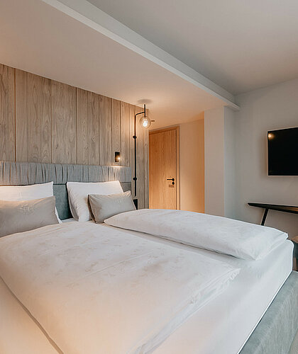 Zweiter Schlafbereich der Berghof Suite Premium mit gemütlichem Doppelbett, Fernseher und Schreibtisch im Hotel Berghof Salzburg.