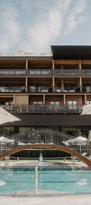 Sommerlicher Poolbereich mit Liegewiese und Sonnenschirmen vor dem Hotel Berghof in Salzburg.
