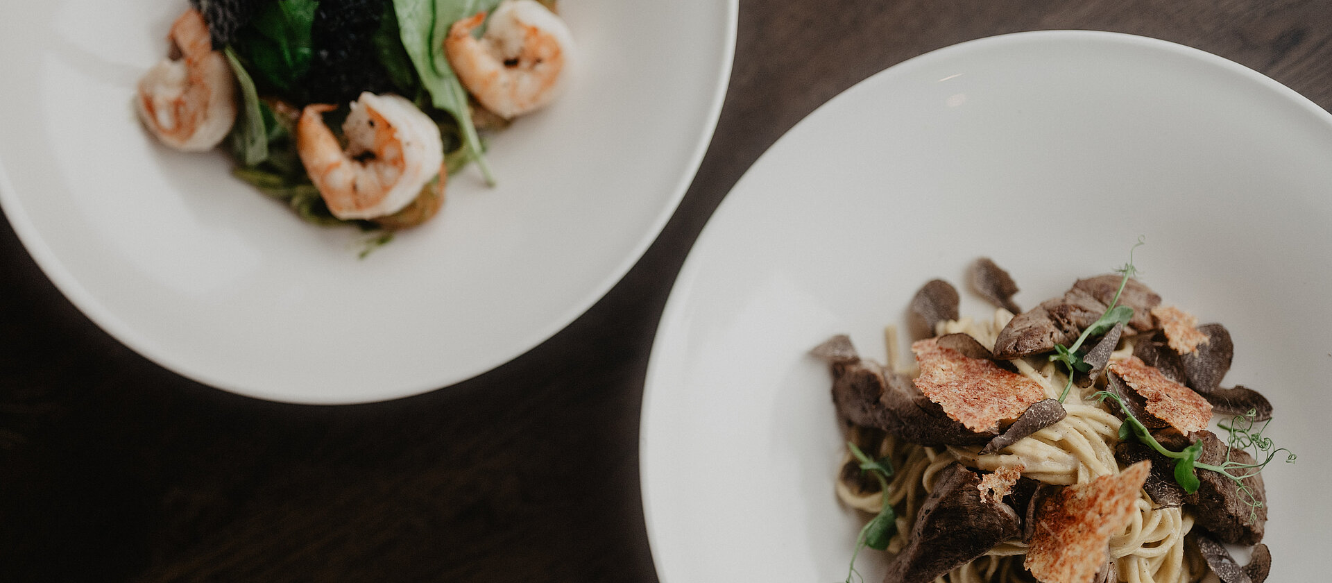 Pasta mit Garnelen und Pasta mit Trüffelscheiben angerichtet in weißen Tellern.