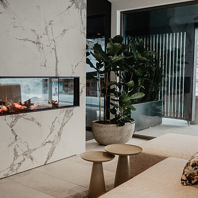 Moderne Kaminlounge im Spabereich des Hotel Berghof mit gemütlicher Sitzgelegenheit und winterlichem Blick in St. Johann, Salzburg