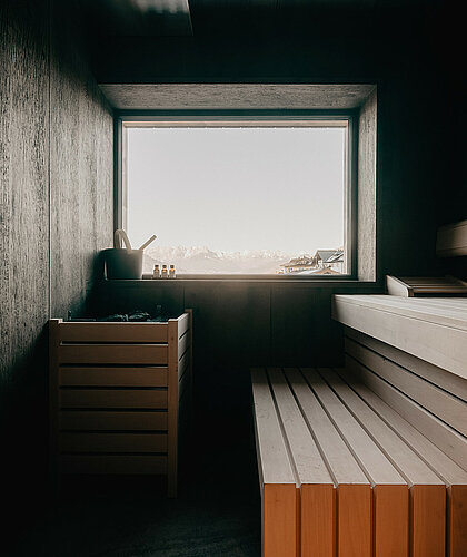 Moderne Sauna mit Holzdesign und Panoramafenster mit freiem Blick auf die Alpenlandschaft im Hotel Berghof in Salzburg.