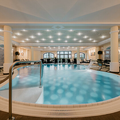 Indoor-Pool für Familien mit Liegen und sanfter Beleuchtung in einem luxuriösen Ambiente.