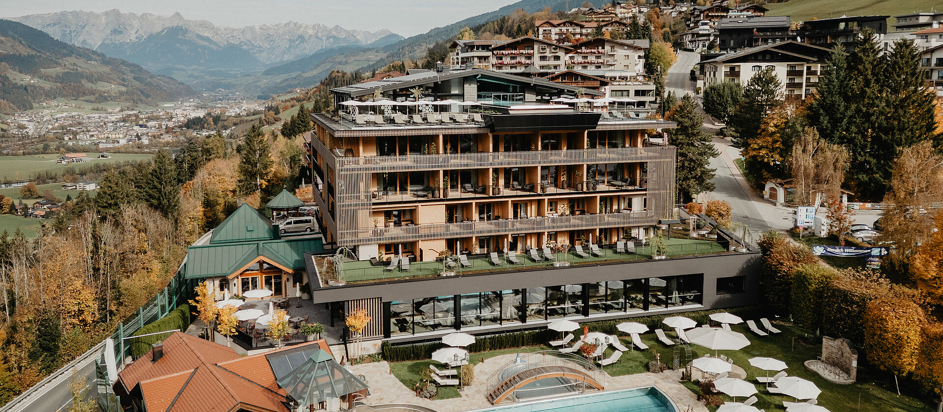 Das Hotel Berghof mit Outdoor Pool umgeben von einer bunten, herbstlichen Kulisse.