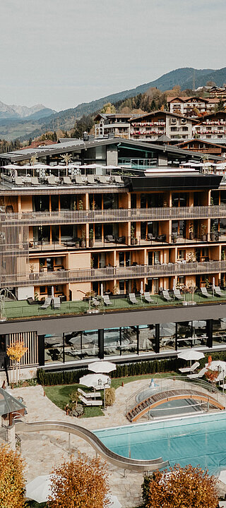Das Hotel Berghof mit Outdoor Pool umgeben von einer bunten, herbstlichen Kulisse.