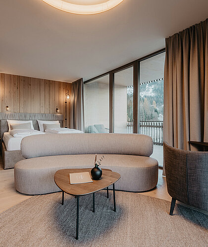 Kombinierter Wohn- und Schlafbereich der Panorama Suite Premium mit edler Einrichtung, großem Doppelbett und gemütlicher Sitzecke im Hotel Berghof Salzburg.