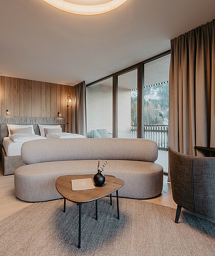 Kombinierter Wohn- und Schlafbereich der Panorama Suite Premium mit edler Einrichtung, großem Doppelbett und gemütlicher Sitzecke im Hotel Berghof Salzburg.