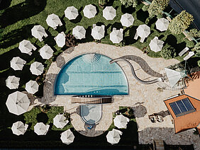 Luftaufnahme des Pools mit Sonnenschirmen und Liegen im Hotel Berghof Salzburg.