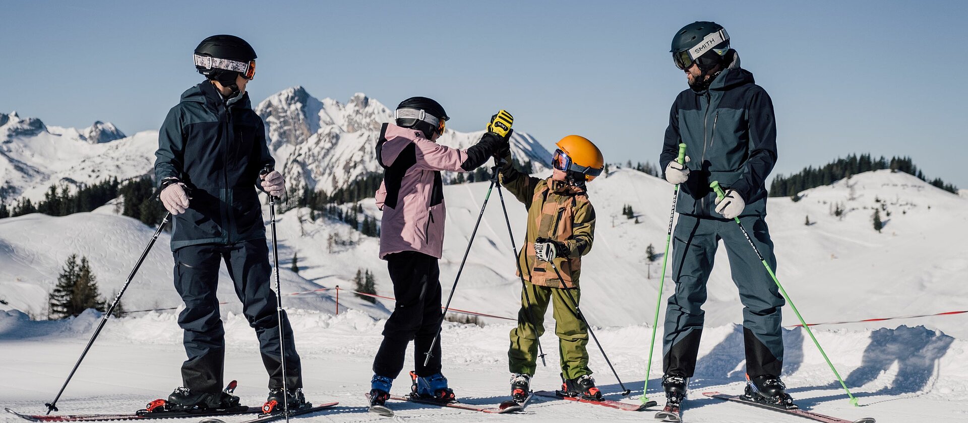 Eine Familie fährt Ski in St. Johann im Pongau und die Kinder geben sich ein High Five.