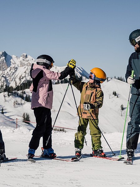 Eine Familie fährt Ski in St. Johann im Pongau und die Kinder geben sich ein High Five.