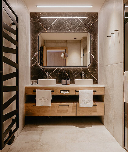 Zweites Badezimmer der Berghof Suite Premium mit eleganten Waschbecken, Marmorakzenten und stilvoller Beleuchtung im Hotel Berghof Salzburg.