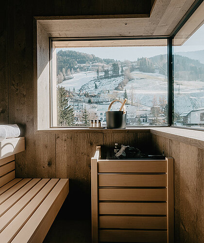 Moderne private Sauna in der Premium Familiensuite mit Panoramafenster und Blick auf die Berge des Salzburger Landes.