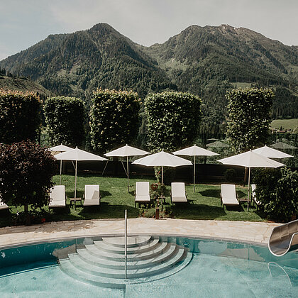 Beheizter Outdoorpool mit Sonnenliegen und traumhaftem Bergblick im Familien- und Wellnesshotel Berghof in Salzburg.