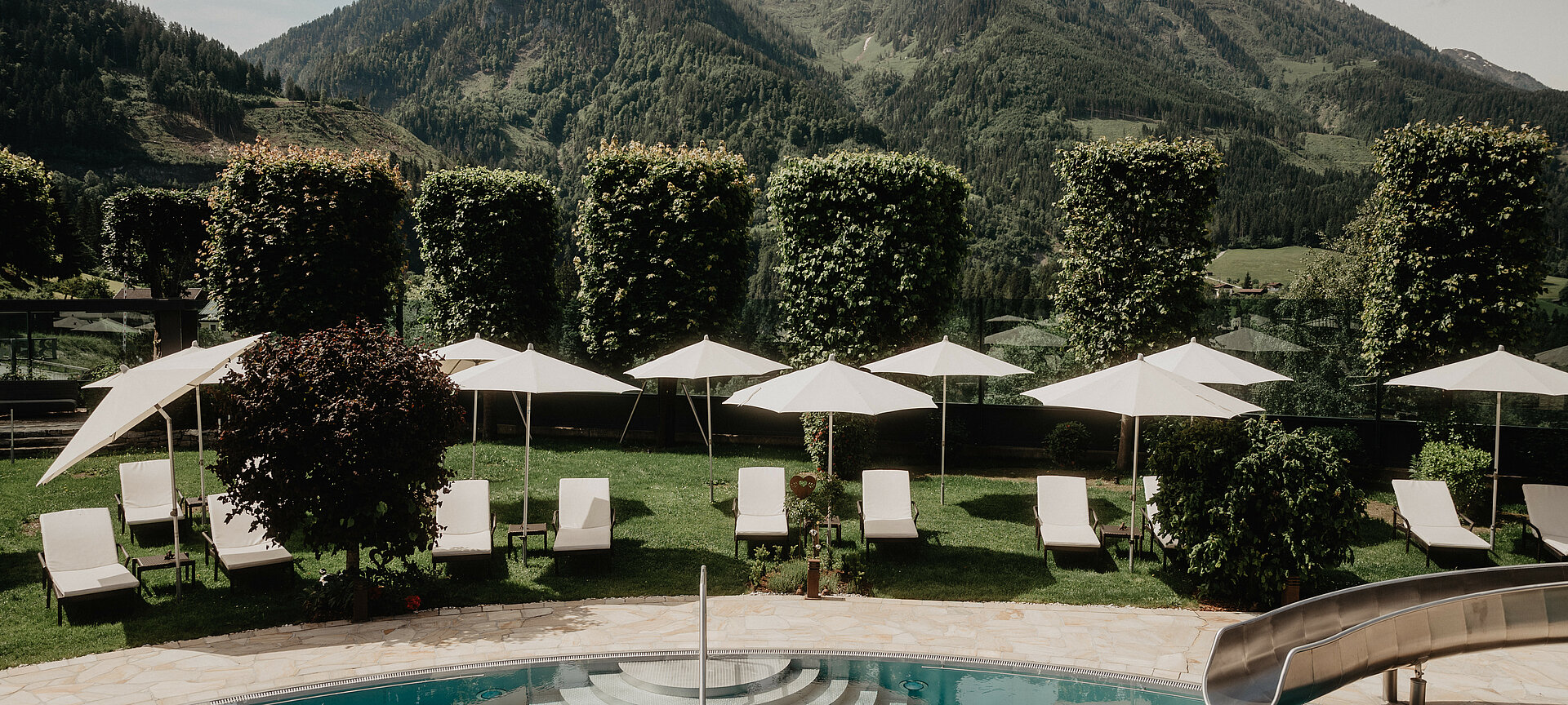 Beheizter Outdoorpool mit Sonnenliegen und traumhaftem Bergblick im Familien- und Wellnesshotel Berghof in Salzburg.