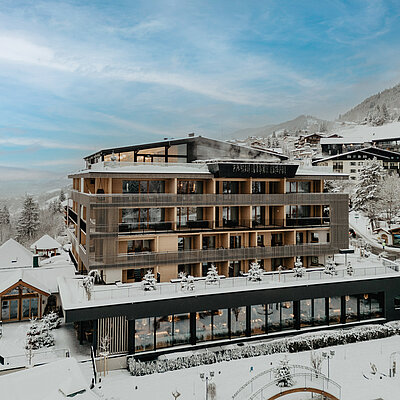 Außenansicht des Hotel Berghof bei Schneelandschaft und blauem Himmel.