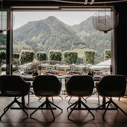 Sitzplatz im Restaurant mit Ausblick auf Alpenberge, Naturgarten und angrenzenden Pool