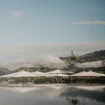 Panoramaaufnahme des Infinitypools im Rooftop Spa des Wellnesshotels Berghof mit Blick auf die umliegenden Berge Salzburgs.