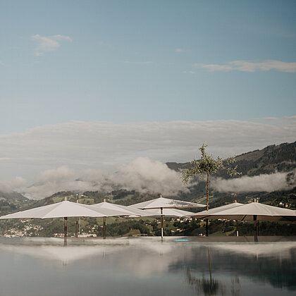 Panoramaaufnahme des Infinitypools im Rooftop Spa des Wellnesshotels Berghof mit Blick auf die umliegenden Berge Salzburgs.