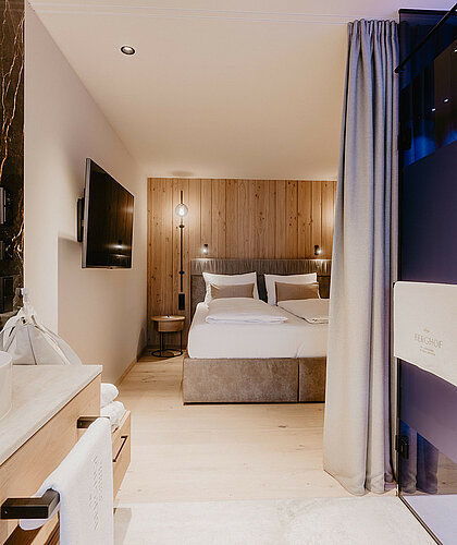 Schlafzimmer der Top Familiensuite mit Boxspringbett, Fernseher und moderner Einrichtung im Hotel Berghof Salzburg.