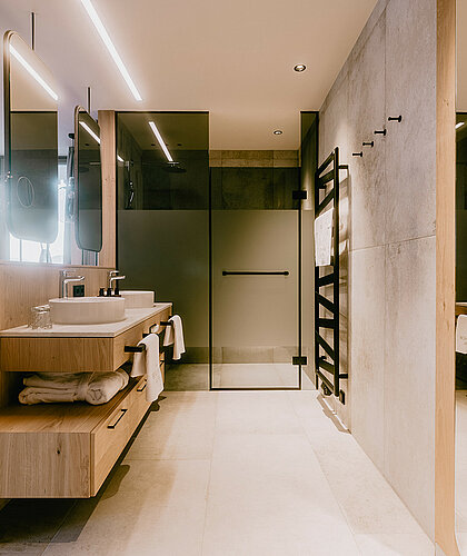 Luxuriöses Badezimmer der Panorama Suite Premium mit Doppelwaschbecken, großzügiger Dusche und hochwertigem Holzdesign im Hotel Berghof Salzburg.