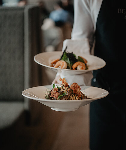 Serviertes Menü mit Pasta, Garnelen und frischen Zutaten – stilvoll präsentiert im Hotel Berghof, Salzburg.