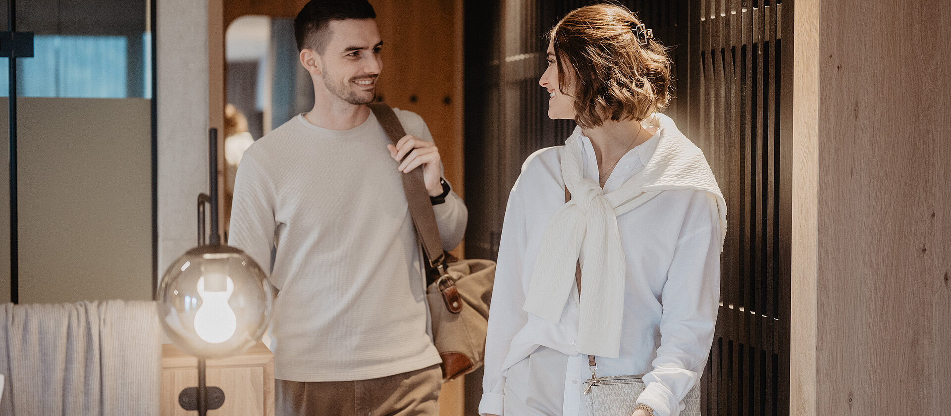 Ein Paar betritt mit seinem Gepäck das Zimmer und sieht sich glücklich an.