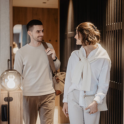 Ein Paar betritt mit seinem Gepäck das Zimmer und sieht sich glücklich an.