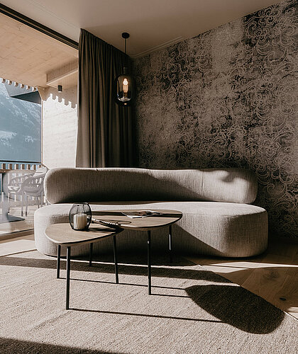 Sofaecke in der Premium Familiensuite mit stilvoller Einrichtung, großer Fensterfront und freiem Blick auf die Berge.
