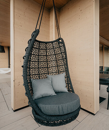 Großer Balkon der Panorama Suite Premium mit Hängesessel, Liegen und atemberaubendem Blick auf die Berge im Hotel Berghof in Salzburg.