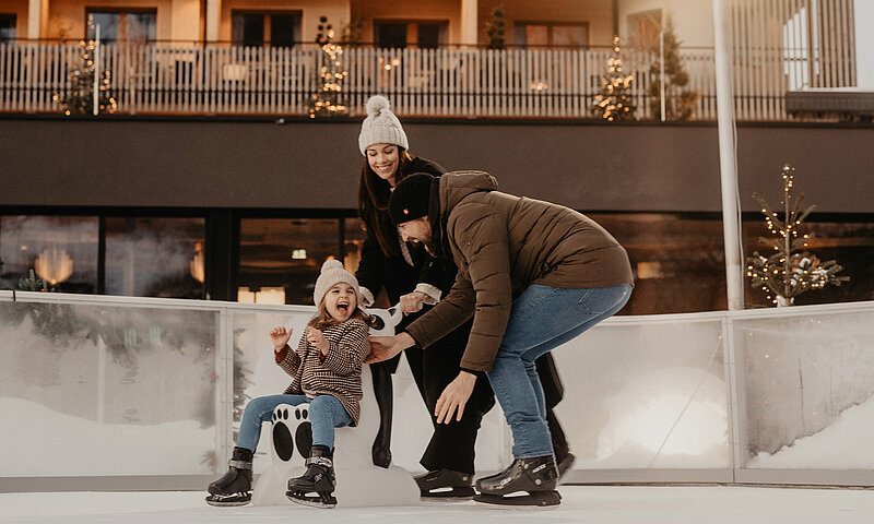 Eine Familie hat Spaß beim Schlittschuhlaufen im Hotel Berghof.
