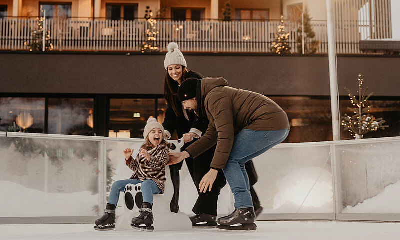 Eine Familie hat Spaß beim Schlittschuhlaufen im Hotel Berghof.